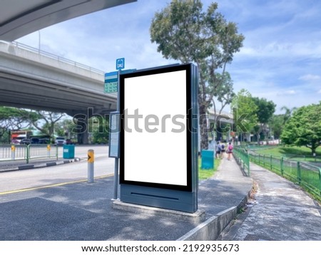 Blank vertical advertising poster banner mockup at empty bus stop shelter by main road, blur background. Out-of-home OOH vertical billboard media display space under expressway highway Royalty-Free Stock Photo #2192935673