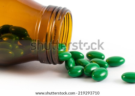 Green pills an pill bottle on white background