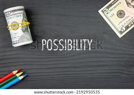 POSSIBILITY - word (text) on a dark wooden background, dollars and colored pencils. Business concept (copy space).