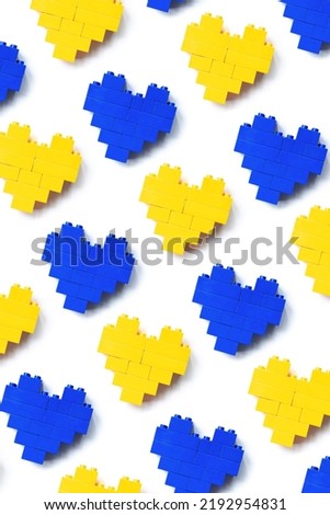 Hearts from Legoblocks as background, minimal geometric pattern from plastic blocks blue and yellow color, shapes heart from child construction. Top view repeat pattern, Toys and games
