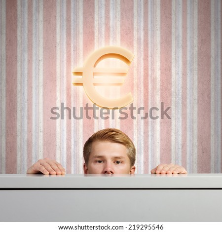 Half of face of young man looking out from under table