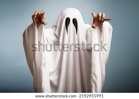 Halloween Concept. A white ghost with black eyes, made from a bedsheet on blue background.