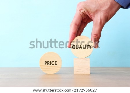 A hand chooses a cube with the word quality, versus price Royalty-Free Stock Photo #2192956027