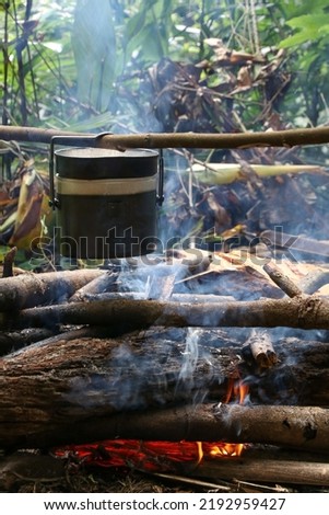 Rice cooking with military pot on bonfire. Camping in deep forest. (The pictures has noise and soft focus)