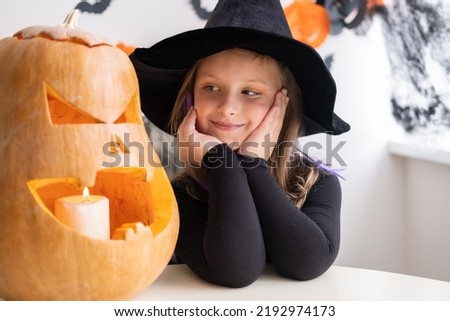 cute girl in costume of witch with pumpkin at home, having fun, celebrating Halloween