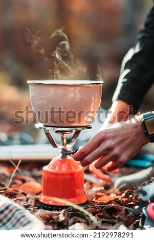 Male hand preparing soup on portable gas stove Royalty-Free Stock Photo #2192978291