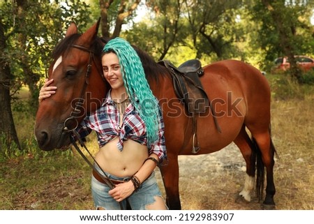 Young woman with curly blue hair with a horse