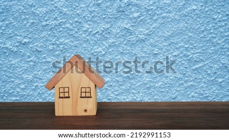 Model of a small wooden house on a light blue background.