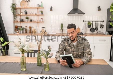 Dispirited serviceman staring at the photo in his hands