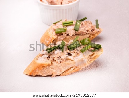 Sandwiches with rillettes, meat pate and fresh chives on a gray vintage background, close-up. Composition with spread meat product on crispy bread, baguette, horizontal view.