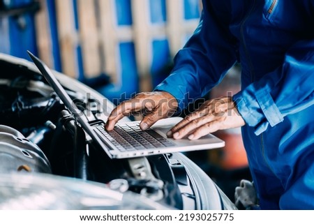 Automotive mechanic repairman using laptop computer and checking engine in the engine room, check the mileage of the car, oil change, auto maintenance service concept Royalty-Free Stock Photo #2193025775