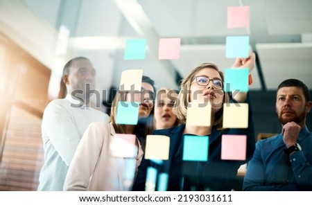 Creative group or business team planning for innovation with sticky notes on glass wall. Coach or leader sharing vision and mission in a meeting. Manager sharing ideas and explaining strategy Royalty-Free Stock Photo #2193031611