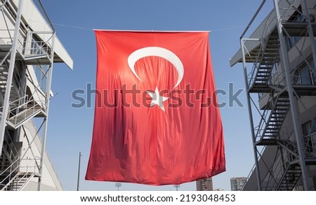 Turkish flag hanging among two buildings.