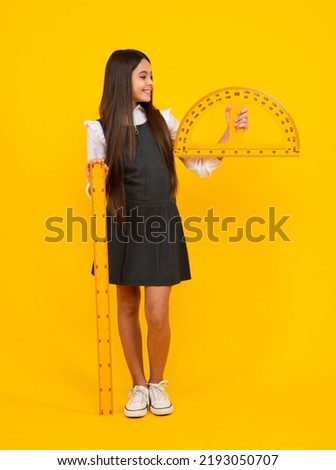 Back to school. School girl hold ruler measuring isolated on yellow background. Happy girl face, positive and smiling emotions.