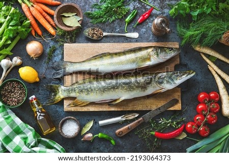 Fresh raw pike perche or zander and pike fish with ingredients prepared for cooking on rustic kitchen table Royalty-Free Stock Photo #2193064373