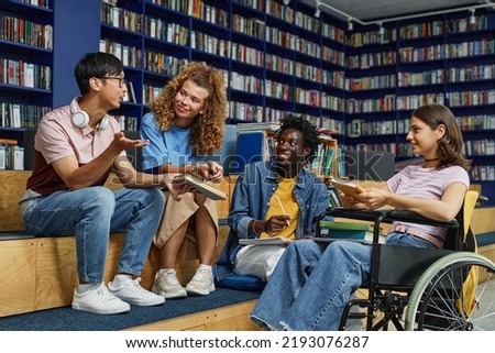 Diverse group of students in college library including young woman in wheelchair enjoying discussion
