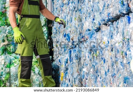 Caucasian Waste Management Worker in Front of a Pile of Pressed Plastic PET Bottles. Trash Sorting Facility. Royalty-Free Stock Photo #2193086849