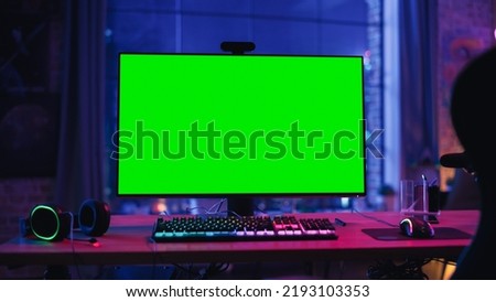Gaming at Home: Empty Gamer Station with Player's Personal Computer with Green Screen Chroma Key Display Standing on a Wooden Desk in Cozy Loft Apartment with Neon Lights. Royalty-Free Stock Photo #2193103353