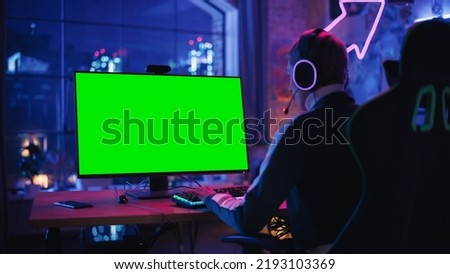 Excited Female Gamer Playing Online Video Game with a Mock Up Green Screen on Her Powerful Computer. Room and PC have Colorful Neon Led Lights. Evening at Home in Cozy Apartment.