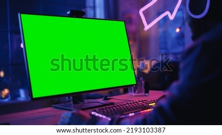 Excited Gamer Playing Online Video Game with a Mock Up Green Screen on His Powerful Personal Gaming Computer. Close Up on Room and PC with Colorful Neon Led Lights. Evening at Home in Loft Apartment.