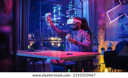 Young Man Using Virtual Reality Headset with Controllers at Home in Loft Apartment. Stylish Black Male Browsing Online, Spending Time in VR Software and Digital Office. POV from Screen Perspective. Royalty-Free Stock Photo #2193103467