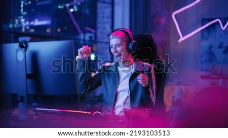 Successful Female Gamer Winning in Online Video Game on Computer. Portrait of Young Stylish Woman in Headphones Playing PvP Tournament with Other Players, Talking with Team on Microphone. Royalty-Free Stock Photo #2193103513