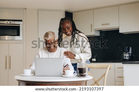 Cheerful senior couple shopping online with a laptop and a credit card. Happy mature couple placing an online order at home. Carefree pensioners spoiling themselves after retirement. Royalty-Free Stock Photo #2193107397