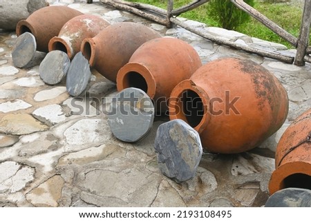 Row of Georgian traditional wine making clay vessels kvevri with stone covers Royalty-Free Stock Photo #2193108495