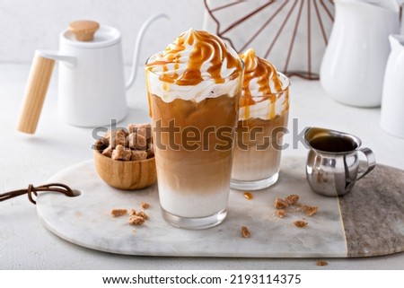 Iced caramel latte topped with whipped cream and caramel sauce, refreshing and sweet coffee drink