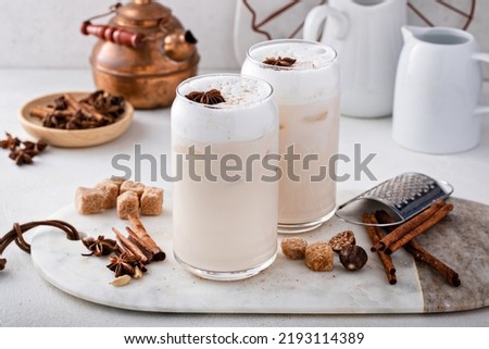 Iced chai latte with warm winter spices topped with milk foam, indian tea drink Royalty-Free Stock Photo #2193114389