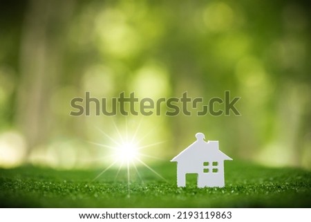 Environmentally eco-friendly real estate house. Small model building property home on grass in green nature ecology. Sustainable energy conservation residential design and sell - rent business concept