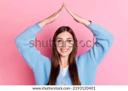 Photo of funky cheerful young woman dressed blue cardigan showing roof overhead smiling isolated on pink color background