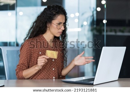 Upset and disappointed businesswoman working in modern office, using laptop and bank credit card to transfer money and shop online in online store, cheated evil employee Royalty-Free Stock Photo #2193121881