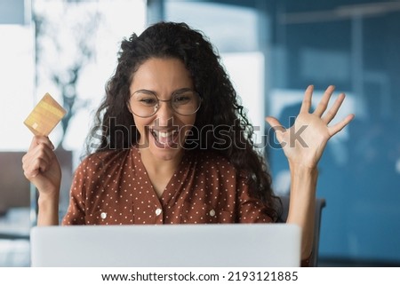 Close-up photo portrait of happy shocked woman, buyer holding bank credit card in hands, business woman looking satisfied in laptop, successful purchase in online internet store