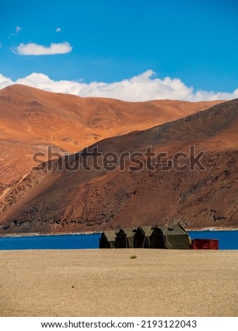 Indian Army tents near Pangong Lake world’s highest saltwater lake dyed in blue stand in stark contrast to the arid mountains surrounding it.Vertical or portrait orientation