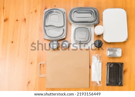 Empty cardboard and plastic fast food takeaway containers on wooden table.