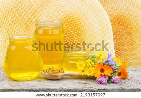 Three jars with honey on the background of beehives with copy space