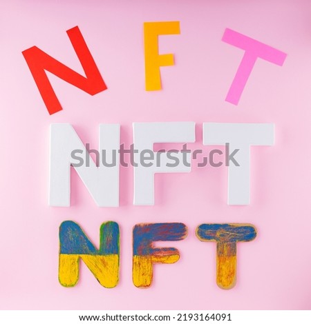 NFT inscriptions on pink background.  Non-Fungible Token folded with multi-colored letters. Crypto art concept. Top view