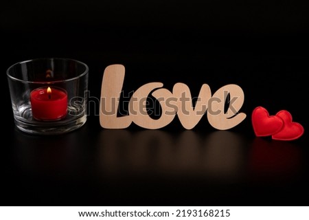 Two red hearts, the word love and a red candle on a dark background for Valentine's Day. Decoration for celebrating the day of love.