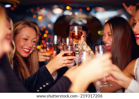 beautiful women clinking glasses in limousine. focus on glasses Royalty-Free Stock Photo #219317206