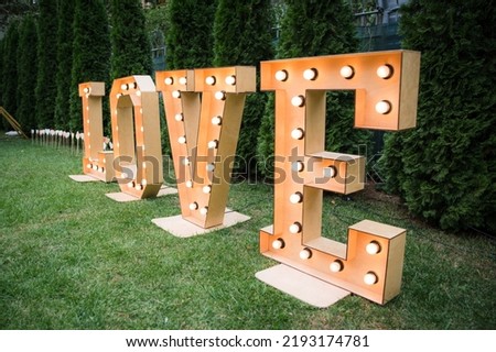 Wedding decor, LOVE letters. big love letters in light bulbs for photo booth at wedding reception in night outdoors. love word lights, stylish evening decor for wedding ceremony.
