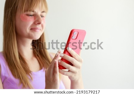 woman in patches under her eyes with a smartphone on a white background