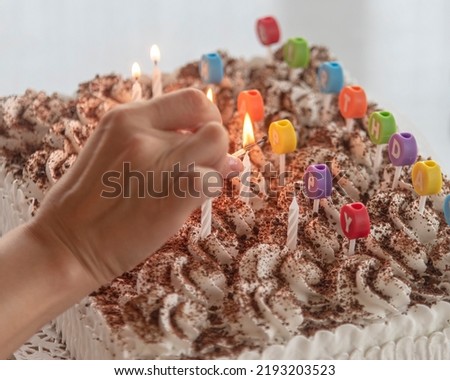 selective focus, woman's hand holding a burning match lights candles on a birthday cake.. birthdays and holidays. copy space.