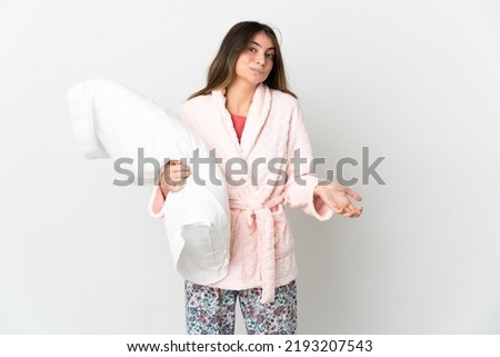 Young caucasian woman isolated on white background in pajamas and making doubts gesture while lifting the shoulders
