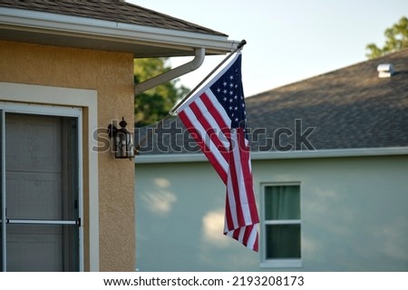 American flag waving on the corner of private residential house, symbol of patriotism