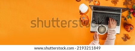 Autumn office work, education flatlay top view copy space. Cozy fall background with laptop, white and orange pumpkins, autumn leaves decor. Woman person hands using a laptop computer from above 