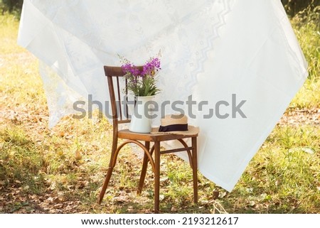 photo zone for outdoors photoshoot with vintage chair, cloth, flower vase and straw hat