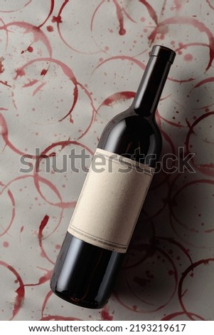 Bottle of red wine with old empty label on a background with stains of wine. Copy space.