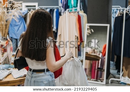 Second hand. Sustainable fashion. Young Latina woman buying used sustainable clothes from second hand charity shop