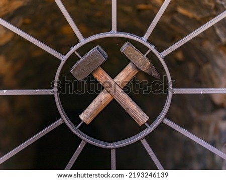 A mining sign with hammer on a lattice door in front of a shaft